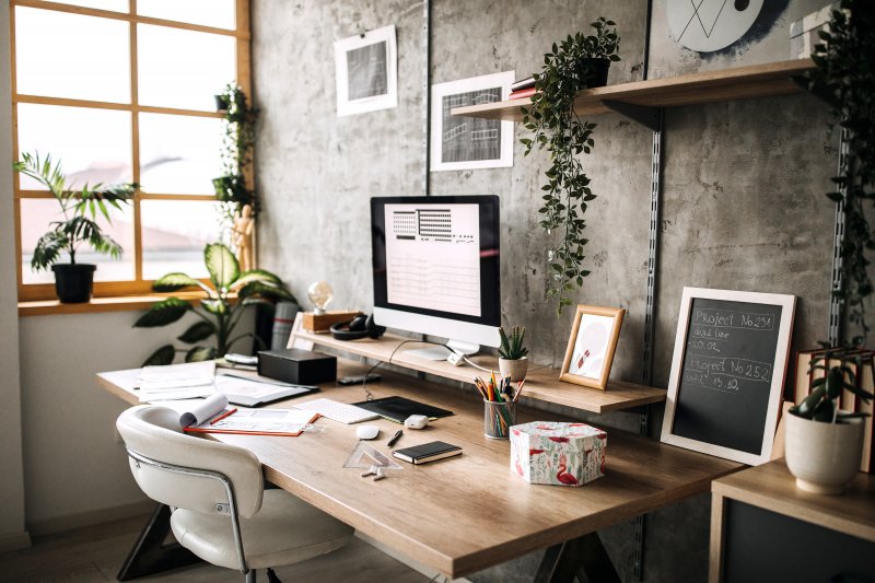 Home office with desk next to a large window facing a concrete wall (Photo by Pekic via Getty Images)